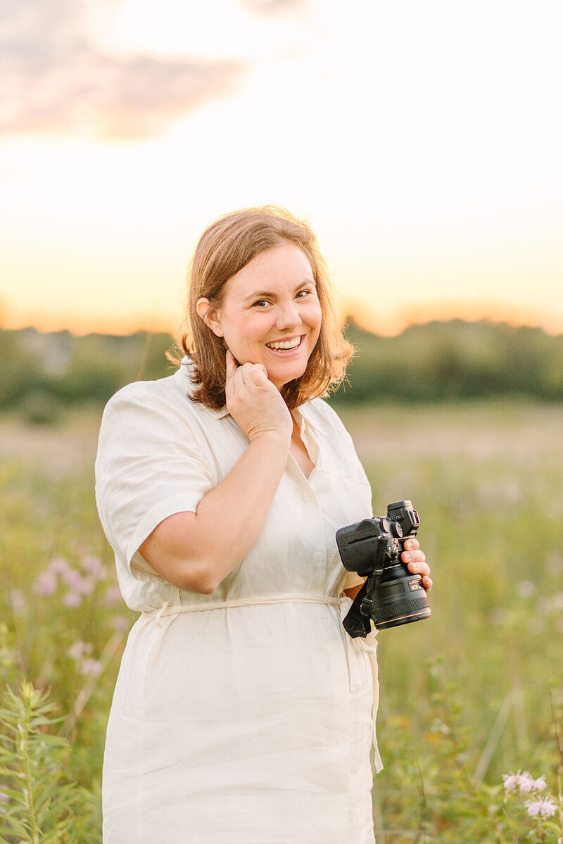 Photographer Kristen Hazelton wearing a purple dress and holding a camera