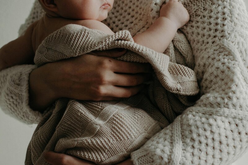 Mother in beige jumper holding baby