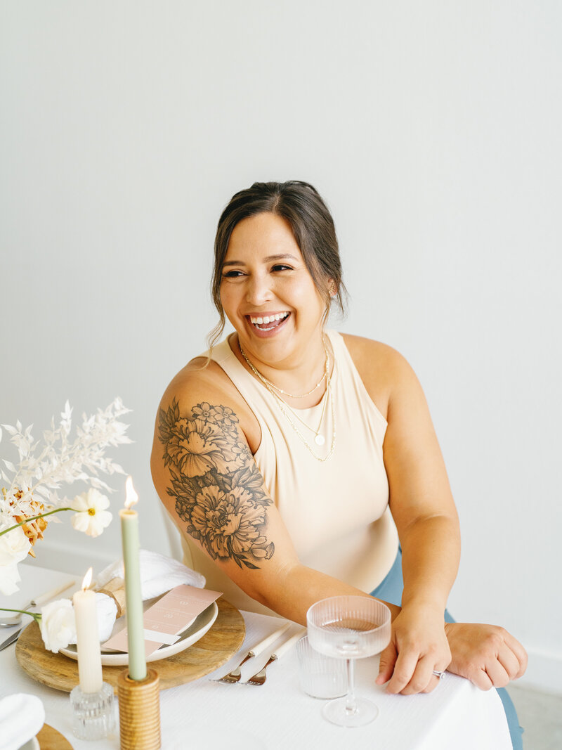 Eventive Designs lead planner smiling at a candlelit table set with blush stationery, soft florals, and neutral-toned decor, representing Austin wedding planning with a personal touch.