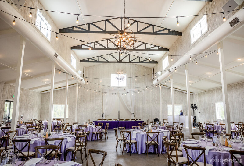 Tables set up for purple wedding reception inside the Woodlands Barn in Colorado