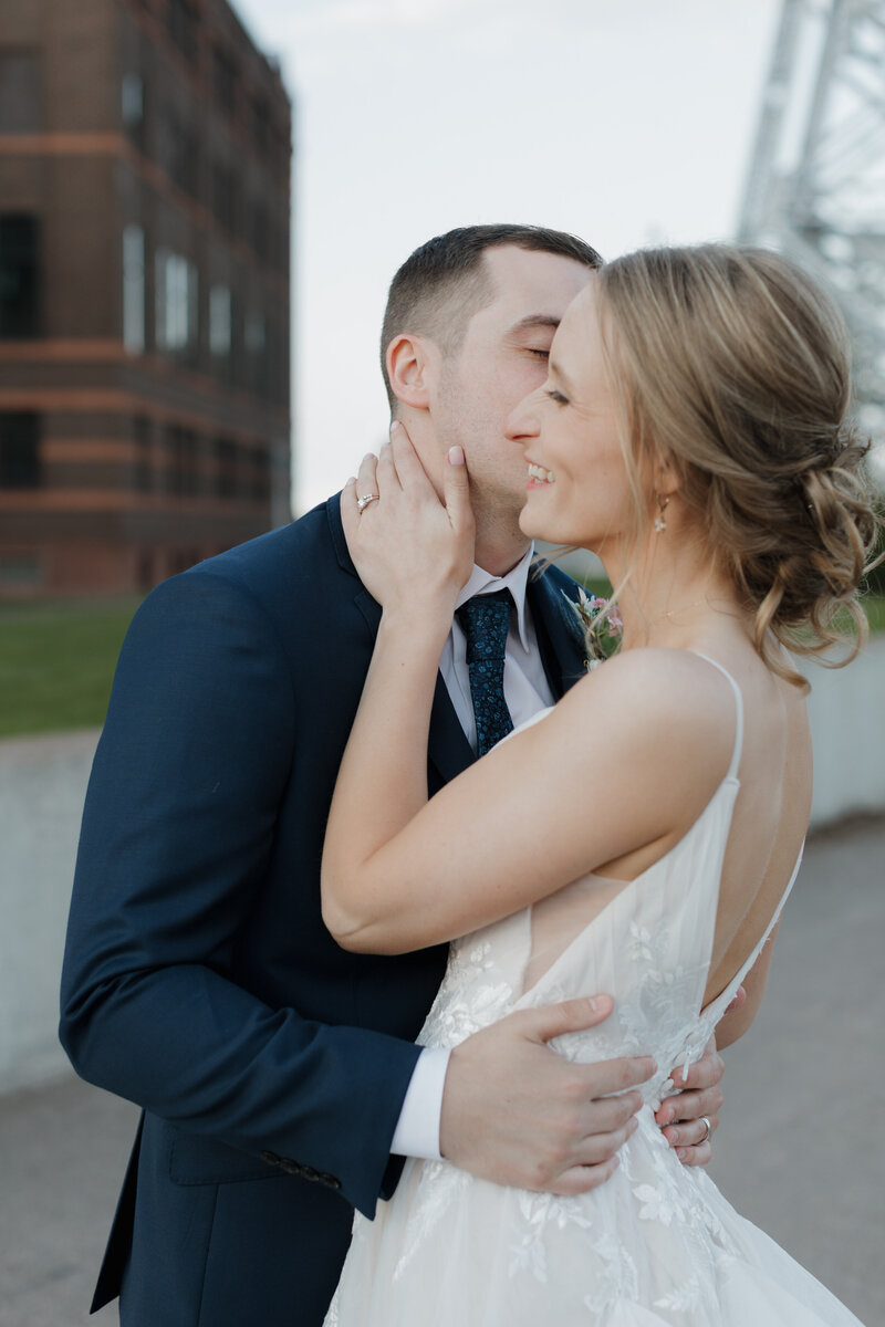 A newlywed kissing their partner's cheek as they smile 