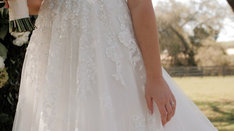 Bride stands in beautiful wedding dress in a field in East Texas