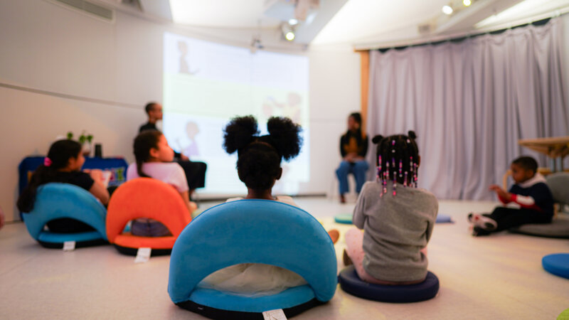 Children listen as Gwendolyn Wallace and MIchaela Ayers read the Light She Feels Inside at the Bronx Children's Museum.