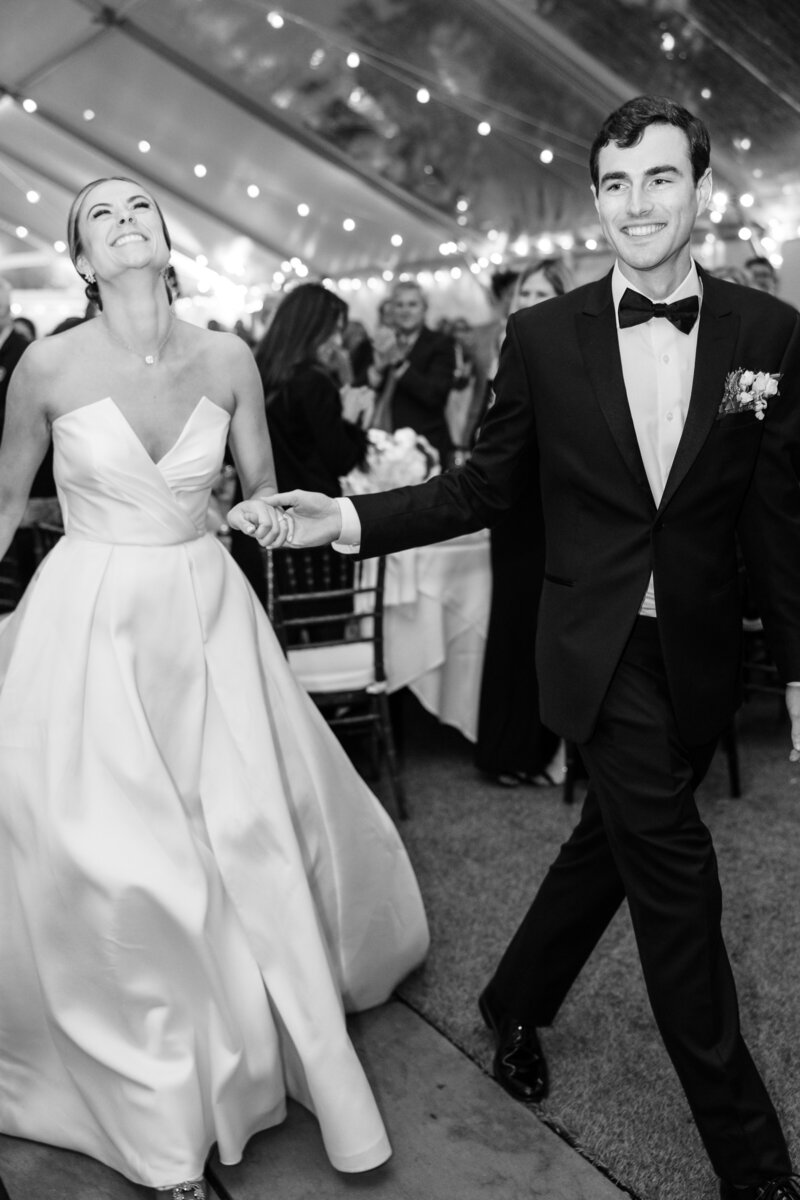 Bride and groom running away from the camera holding umbrellas, with the bride looking back at the camera