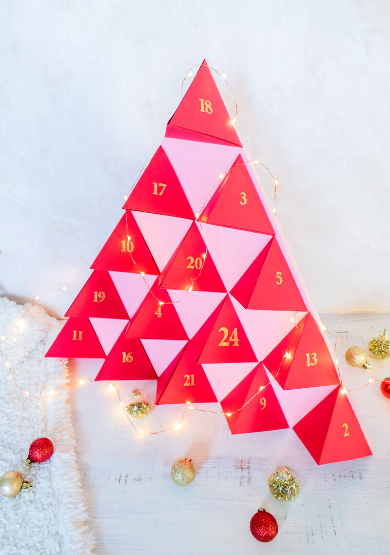 DIY Calendrier de l’Avent en forme de sapin rouge photographié sur fond blanc lumineux The Helloday.
