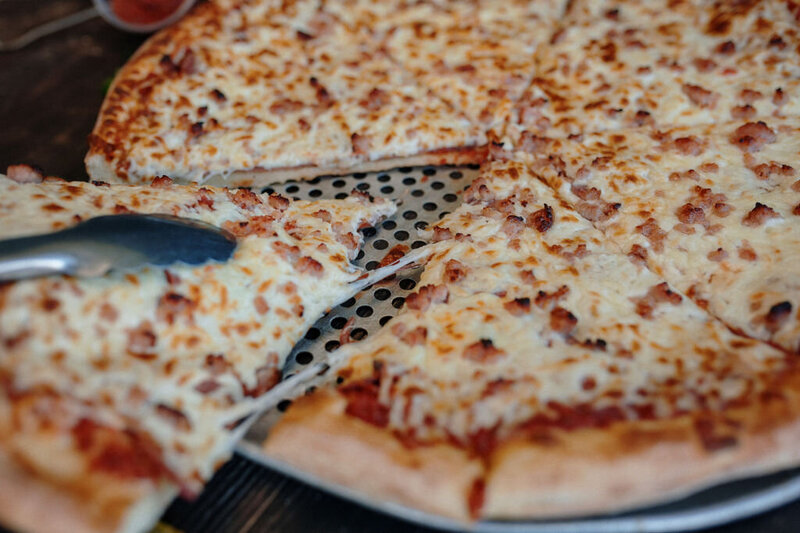 Hot and cheesy Redo’s pizza slice being lifted from the pan—loaded with stretchy mozzarella and crispy crust in Nova Scotia