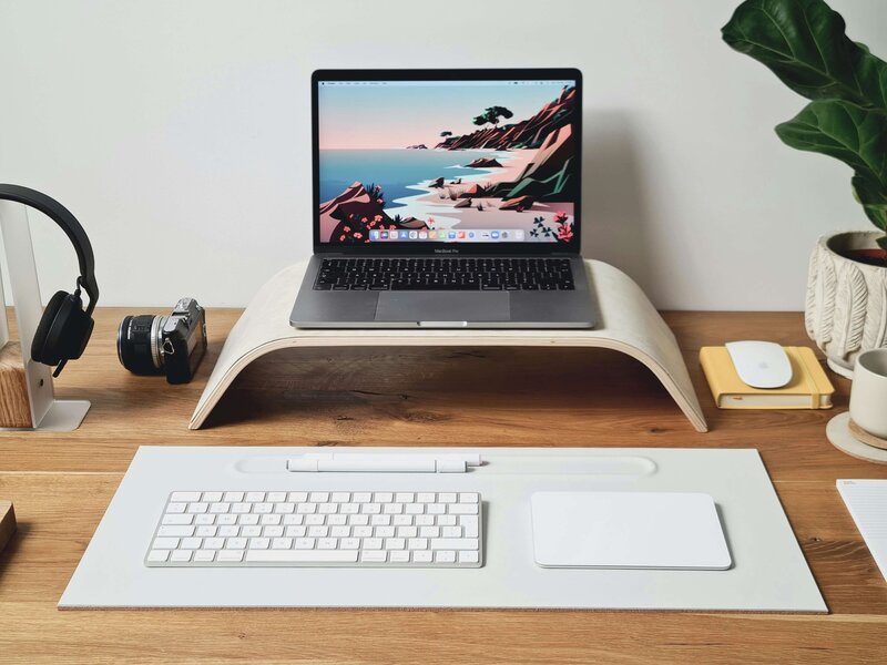 Minimalist home office desk setup with laptop, camera, headphones, and organized workspace for wedding photographers using HoneyBook.
