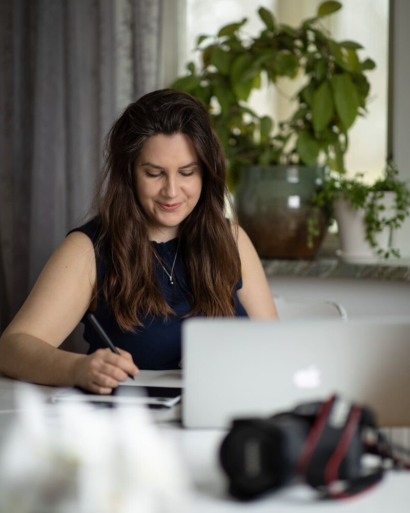 leende kvinnlig fotograf sitter vid dator