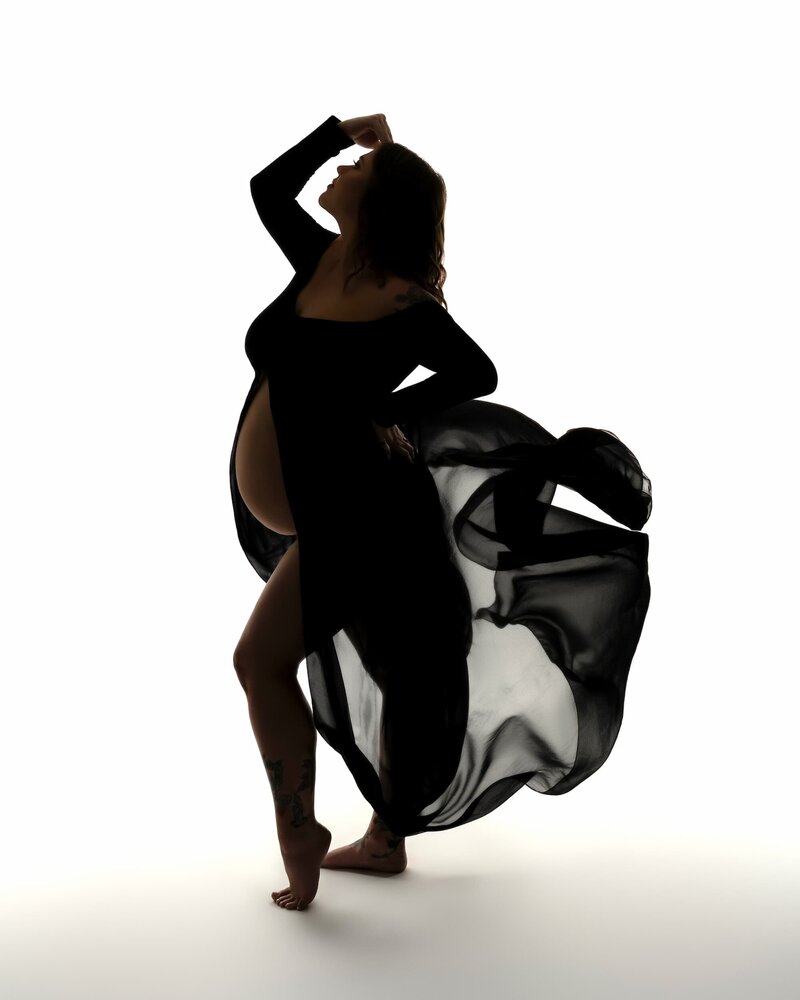 Silhouetted figure in a flowing black fabric captured mid-motion