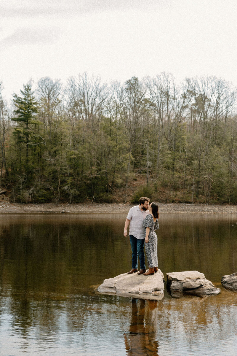 Engaged couple standing by the lakeside, sharing a quiet moment during their engagement session in New York City