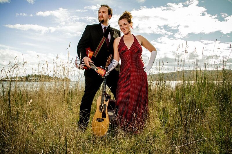Music Duo Portrait Mad For Joy standing in grass field in suit and evening gown with gloves with instruments