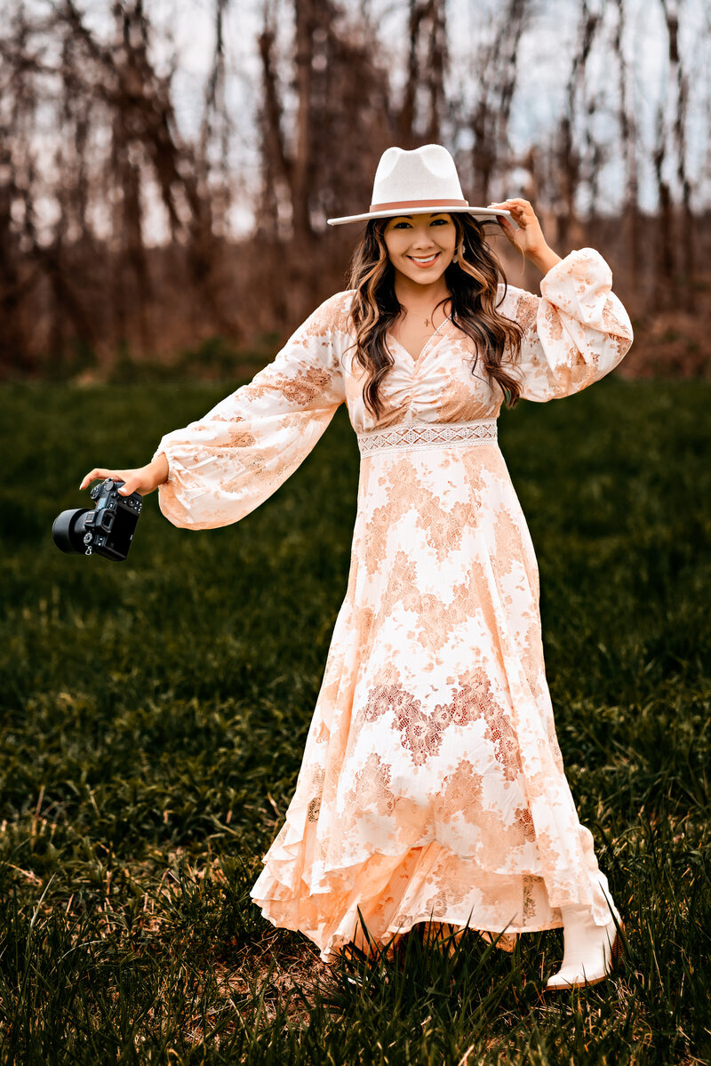 Emily Belanger Photographer dancing in field with camera