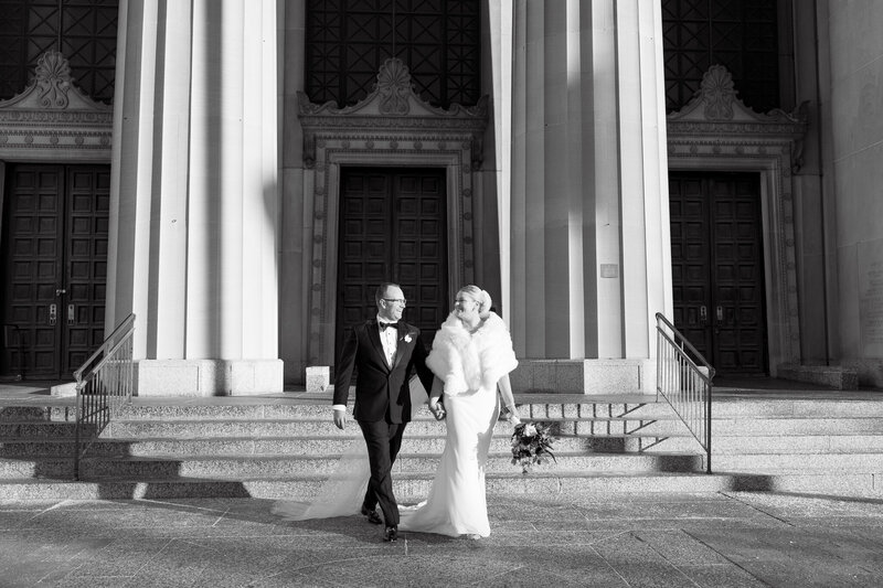 black and white photo of a bride and groom walking hand in hand