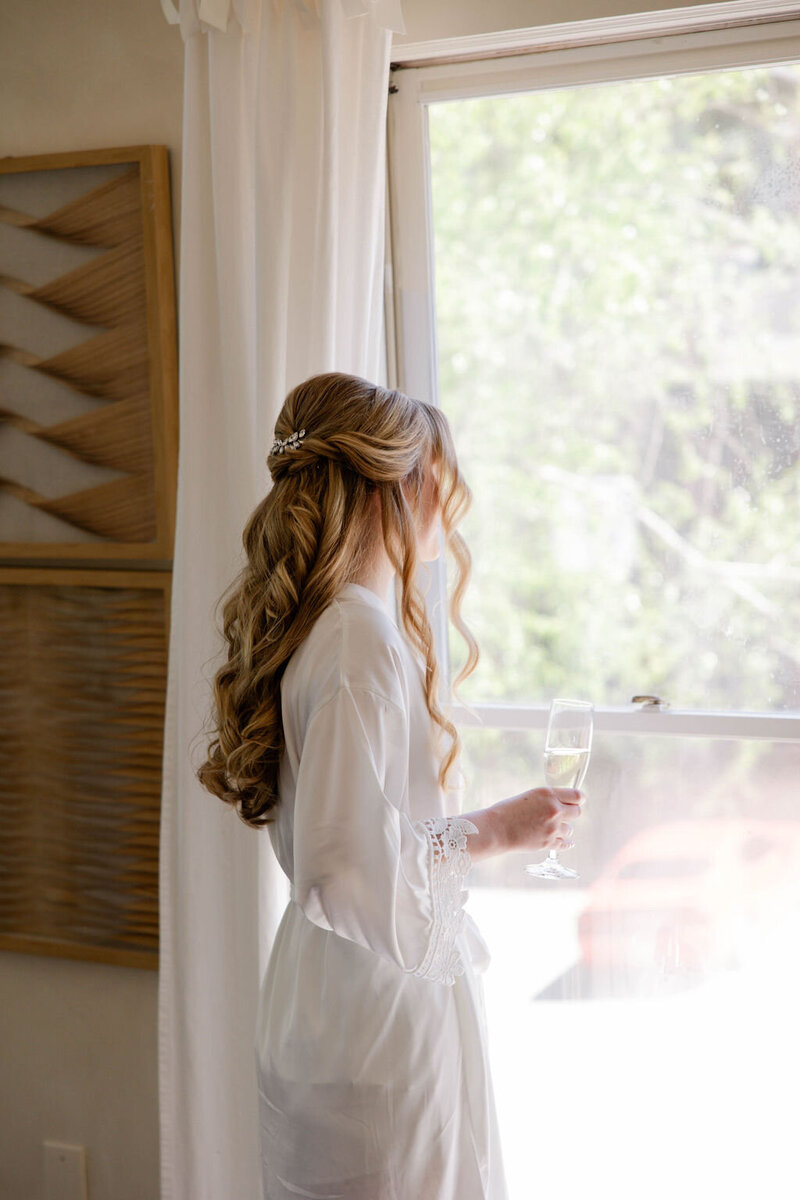 bride holding champagne looking out window atlanta wedding venue