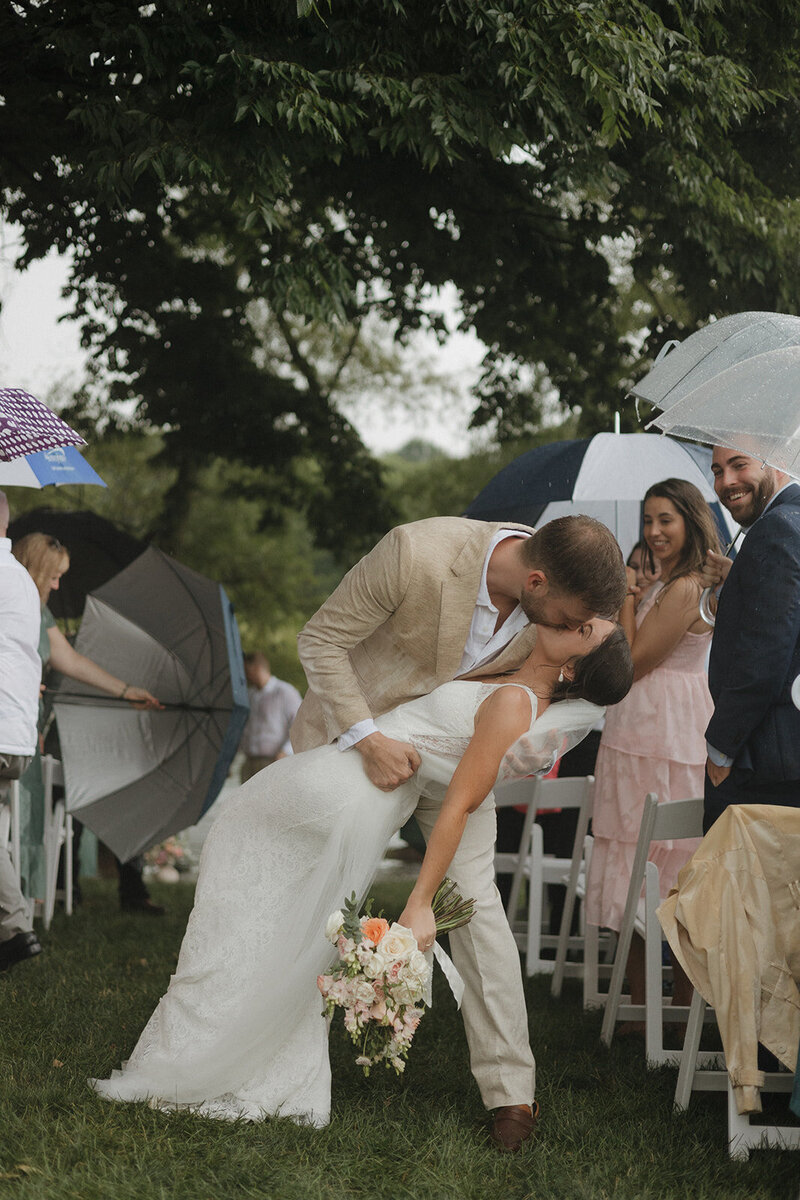 grooms dips bride walking back down aisle after getting married