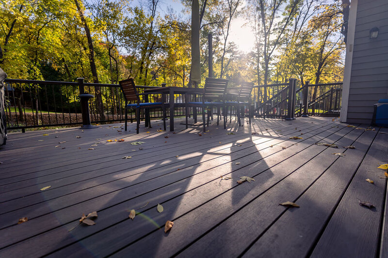 Low angle of a TimberTech Advanced PVC deck during sunset on an autumn day amidst fall foliage. 