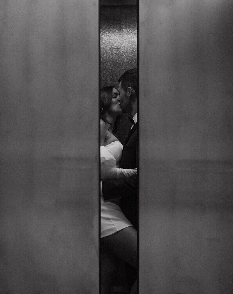 the bride and groom are kissing in the elevator