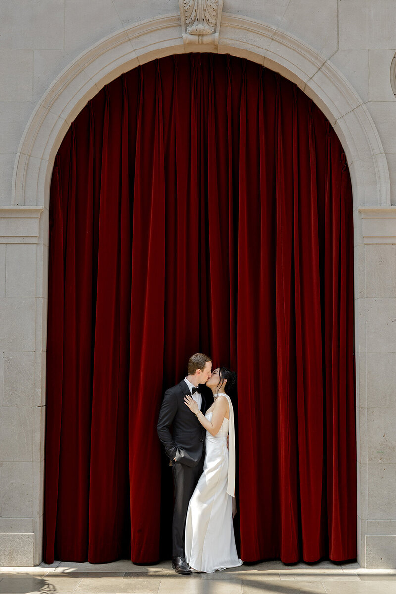 bride and groom in front of the red curtain in Edward's Court at The Columbus Museum of Art Ohio