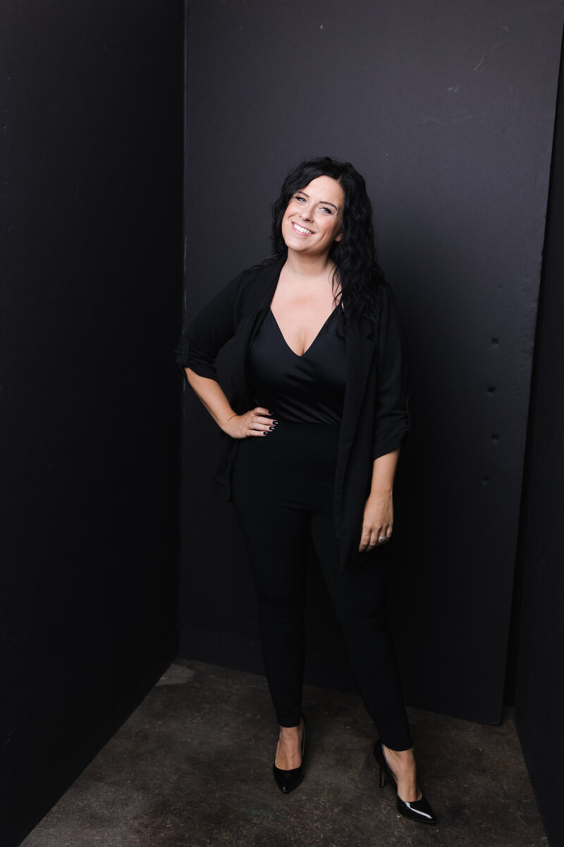 Woman dressed in all black and wearing air jordans standing in a photography studio in front of event rentals and linens