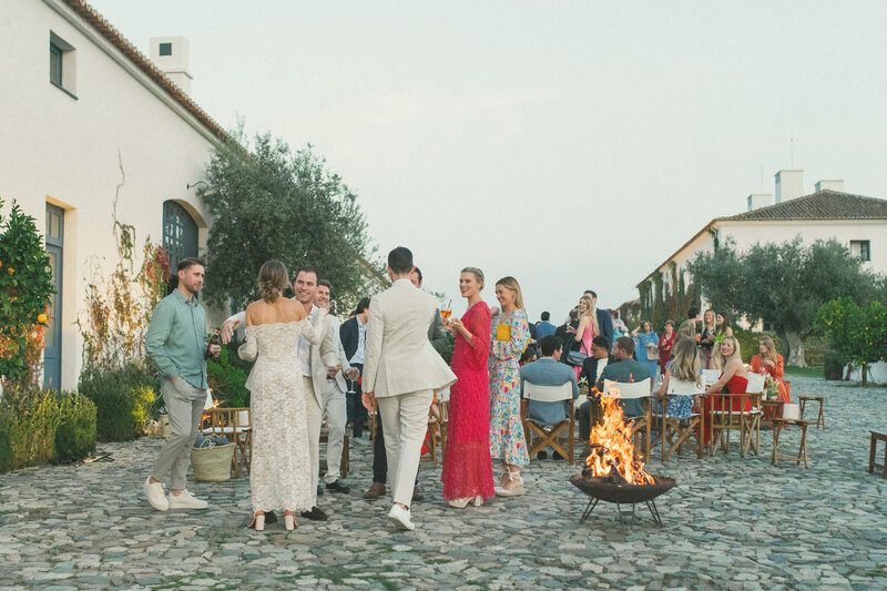 Wedding guests mingling by the fire pit during the couple's welcome dinner in Alentejo, Portugal