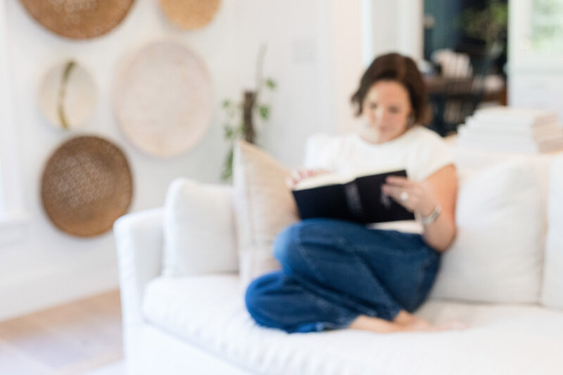 Dinah sitting on her couch with her legs curled up under her reading a book