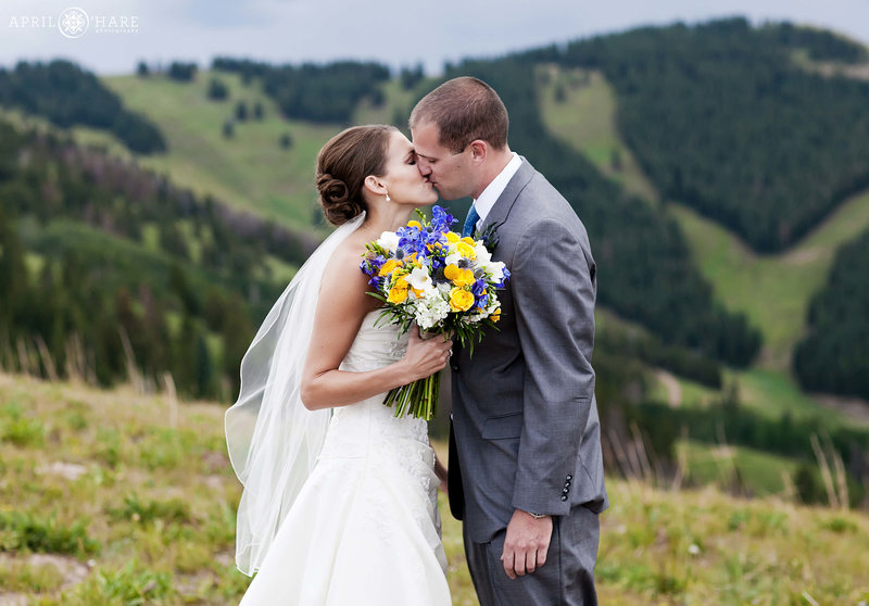 Couple kissing with views of Vail Resort Ski Slopes in backdrop at Holy Cross Event Deck in Vail Colorado