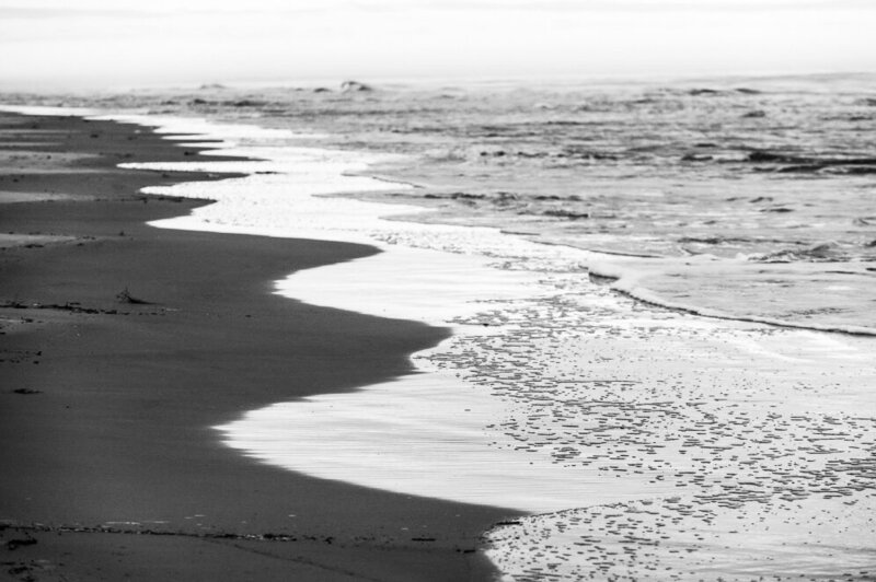 black and white photo of ocean waves breaking on the shore