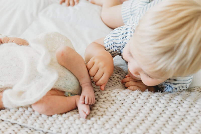 baby girl in a white romper smiling while dad holds her and kisses the top of her head