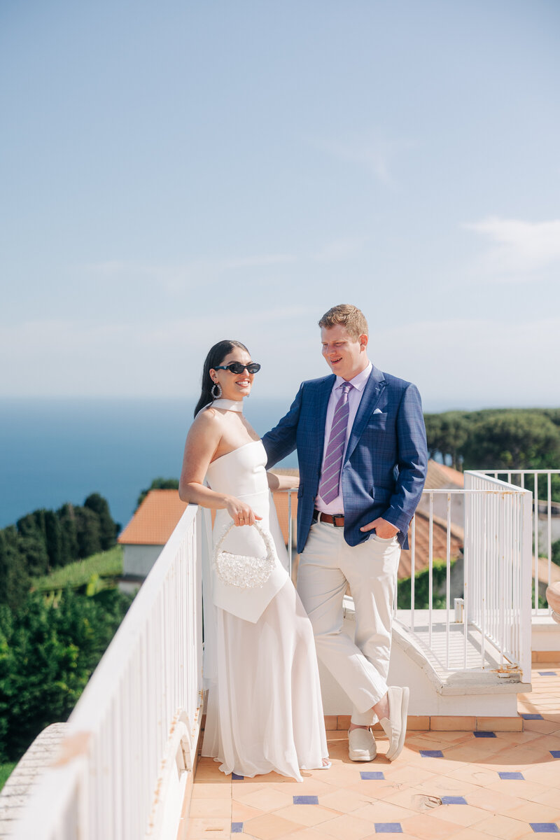 A bride and groom sharing a tender moment on the beach with their foreheads touching, the bride holding a bouquet, captured by a luxury wedding photographer.