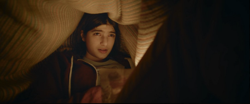 A teenager alone in a locker room, framed with minimalism and emotional distance.