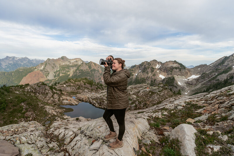 Montana Elopement Photographer poses in front of alpine lake in Glacier National Park.