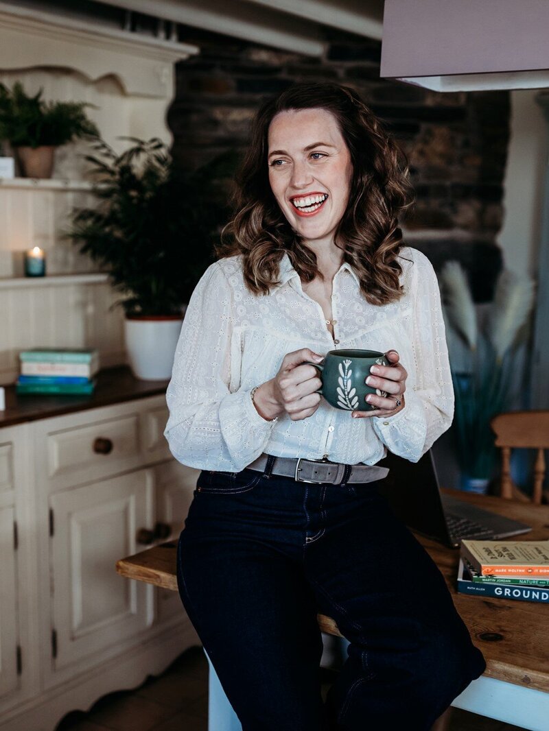 Dr Kate smiling warmly with a coffee cup, creating a welcoming environment for online therapy clients
