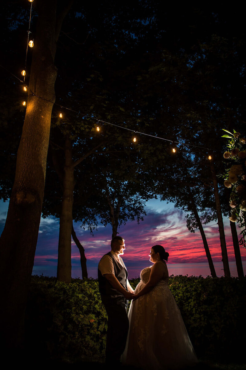 bride and groom holding hands  at cottage overlooking huron county sunset