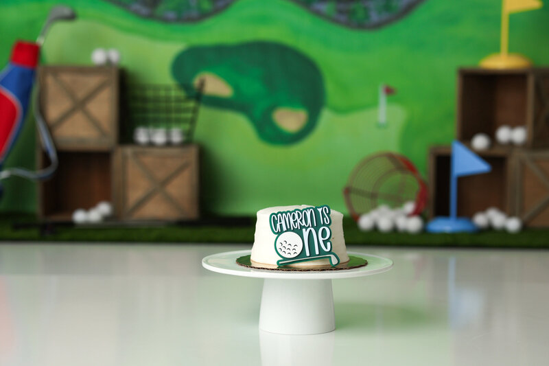 One year old Tampa baby enjoying a personalized luxury cake smash session with golf themed decorations