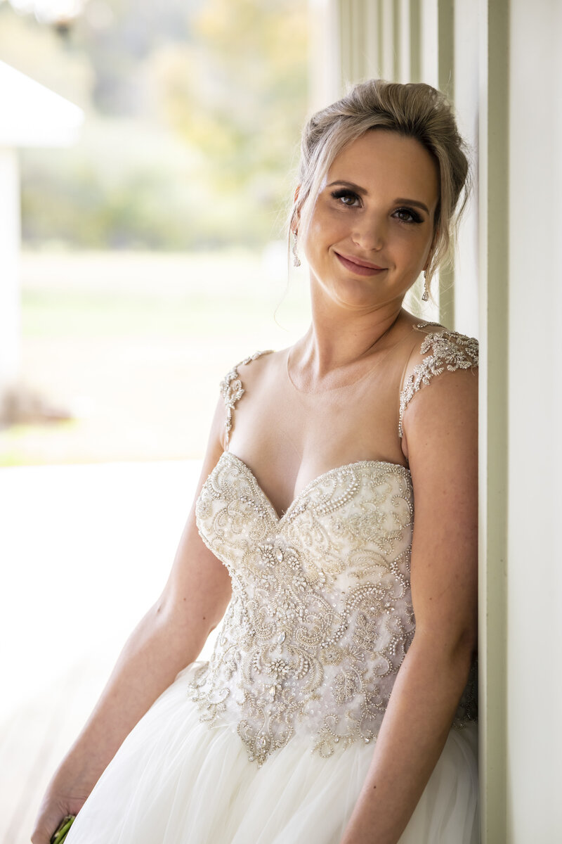 Bride smiling while leaning on doorframe.