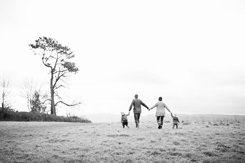 A family of four holding hands while walking in a field in the Surrey countryisde