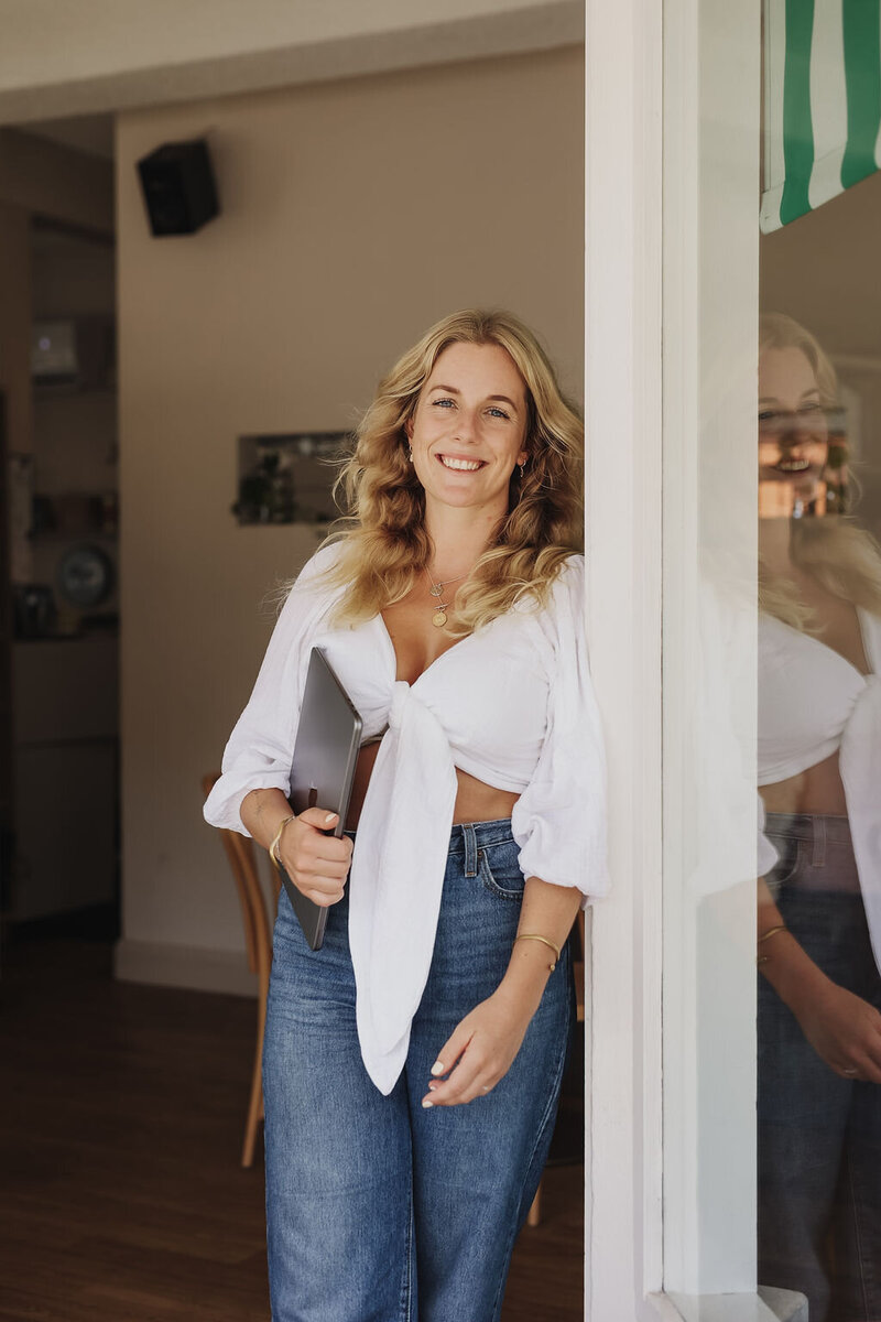 Woman standing in an entrance holding a laptop
