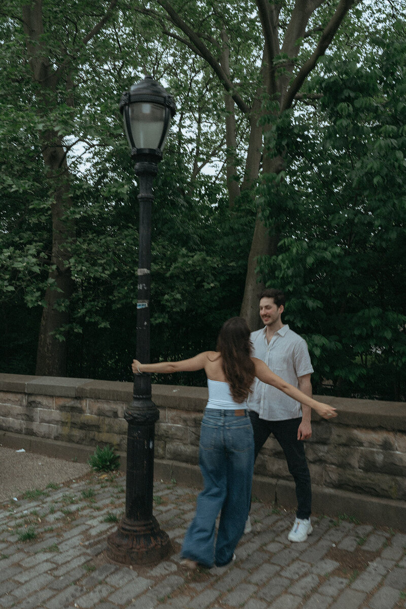 couple posing with light pole during NYC engagement photos, captured by Elsie Goodman, an NYC engagement and couples photographer
