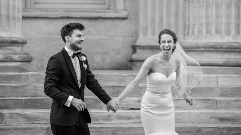 Bride and groom holding hands and laughing in Old City Philadelphia, captured in a photojournalistic style by Fox & Brazen.