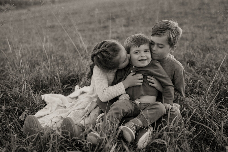 Black and white three children sitting in field together