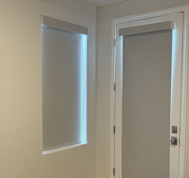 Inside mount roller shade beside an outside mount roller shade on a door, showing light gaps on both