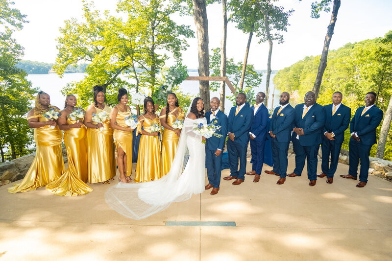 A wedding party poses after the ceremony in front of the lake