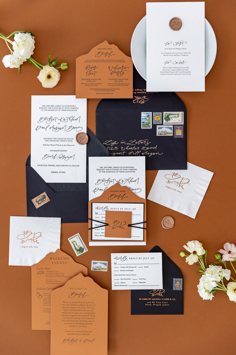 Customized calligraphy flat lay featuring wedding invitations, envelopes, flowers and more represent full service design by Life in Letters.