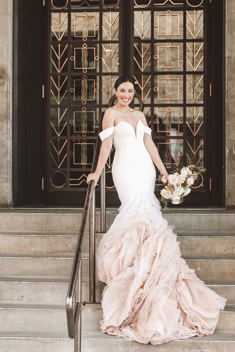 Bride standing on the stairs outside of the Kimpton Armory Hotel in Bozeman, MT.