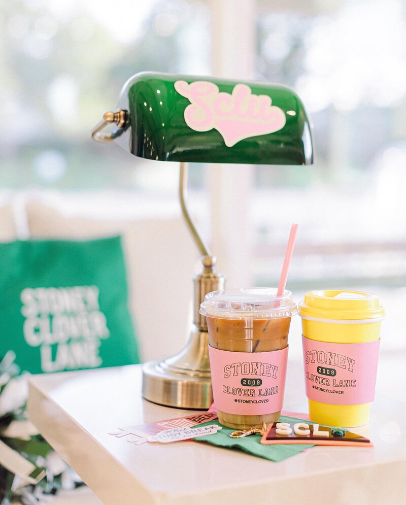 Two cups with coozies sitting on a table beside a lamp