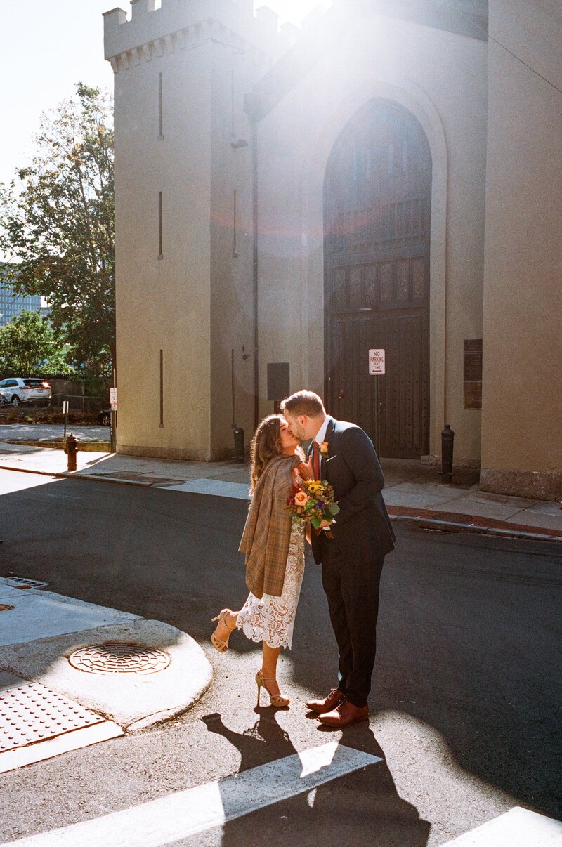 Soft film portrait of a bride and groom smiling at each other under string lights on their wedding day — captured by a film wedding photographer at Castillo Holliday Photo + Film.