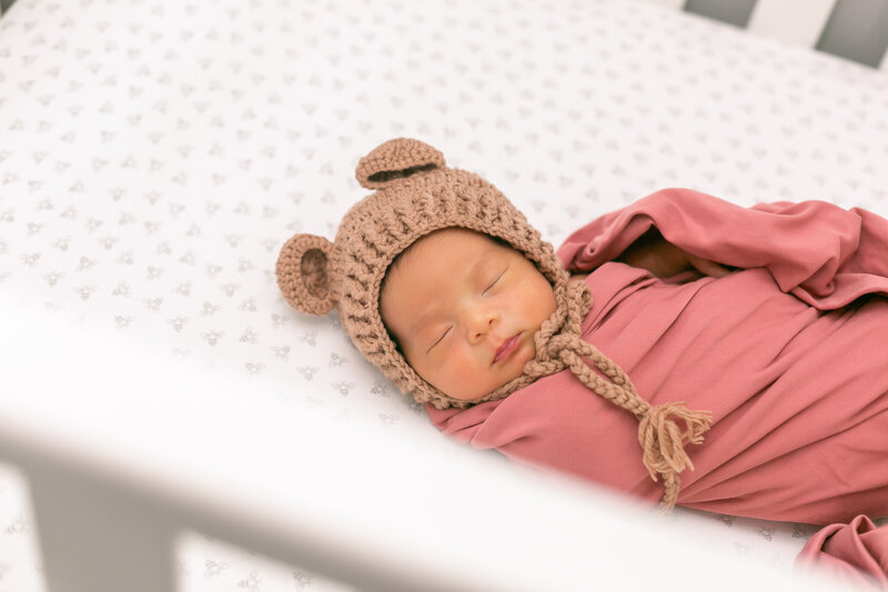 Newborn swaddled in a cozy blanket with teddy bear hat– lifestyle newborn photography in Columbia SC