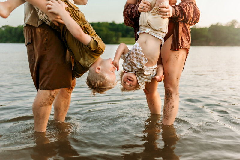 Brother hung upside down by mom and dad in Kansas City lake for family photo session.