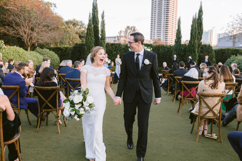 Bride and groom kissing with their reception and guests in the background