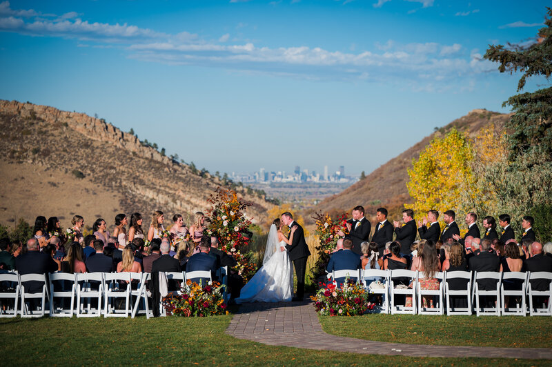 A bride and her bridesmaids wearing pajamas and heart shaped sunglasses stand on the steps of the getting ready house at The Barn at Raccoon Creek in Colorado.